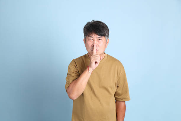 The senior Asian man with casual clothes standing on the blue background.