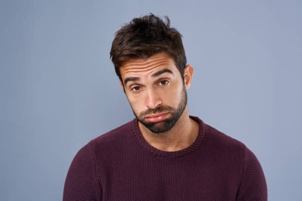 Studio shot of a handsome young man looking sad against a gray background